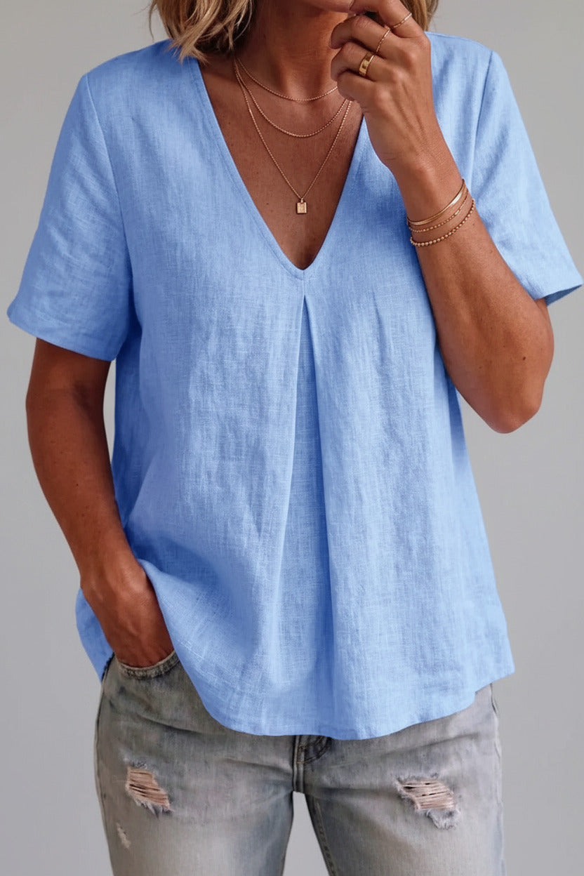 Person wearing a light blue shirt and ripped jeans indoors.