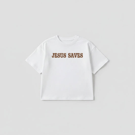 White t-shirt with 'JESUS SAVES' text on a wooden surface with shoes and newspaper.