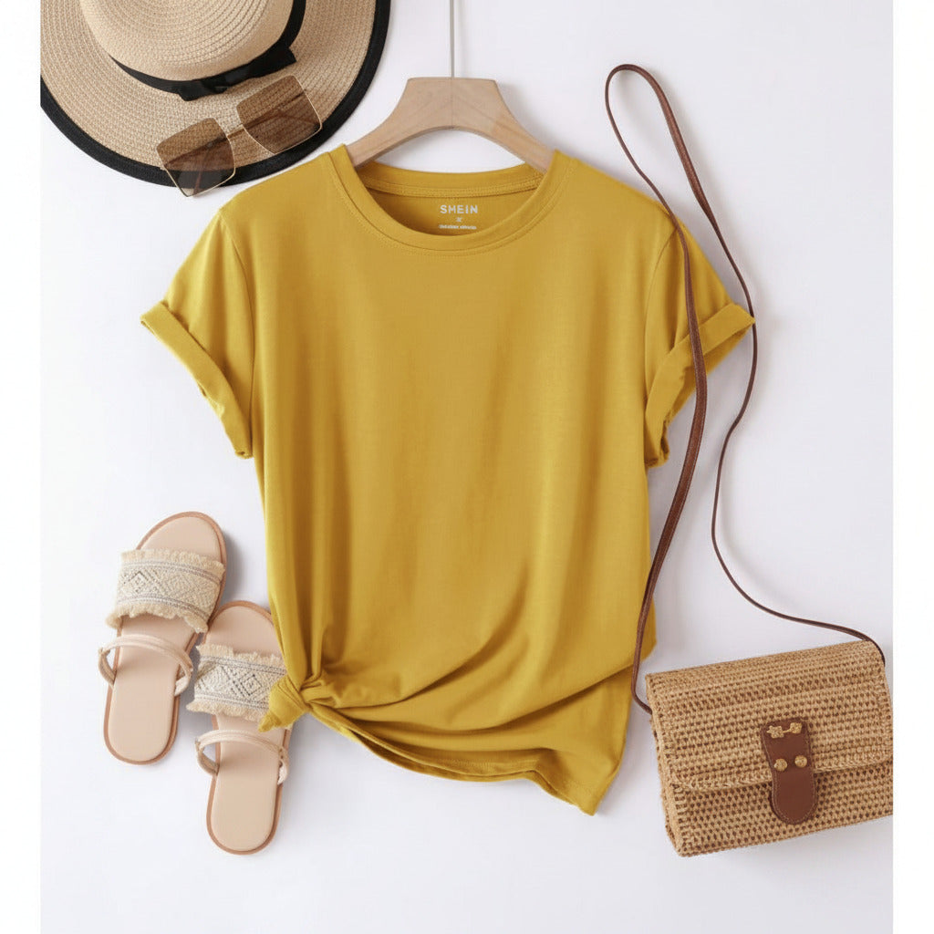 Yellow t-shirt on a hanger with a hat, sandals, and bag on a white background