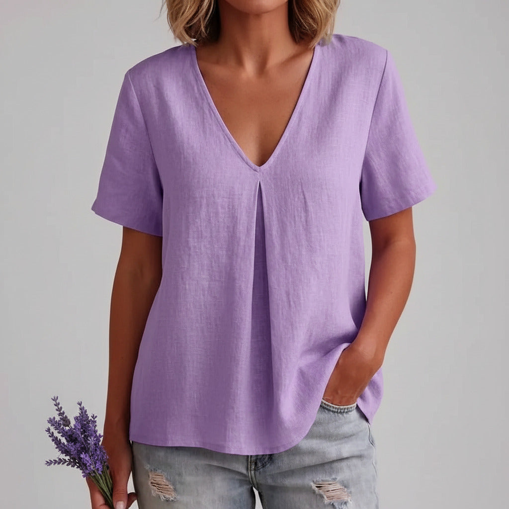 Person wearing a purple shirt and ripped jeans with a dark background
