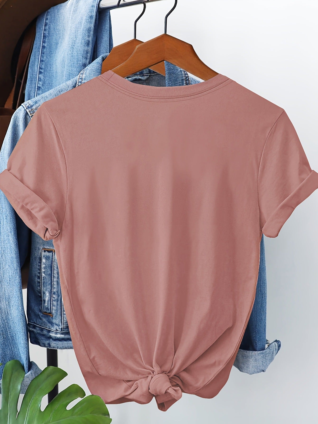 Pink t-shirt on a hanger with jeans in the background