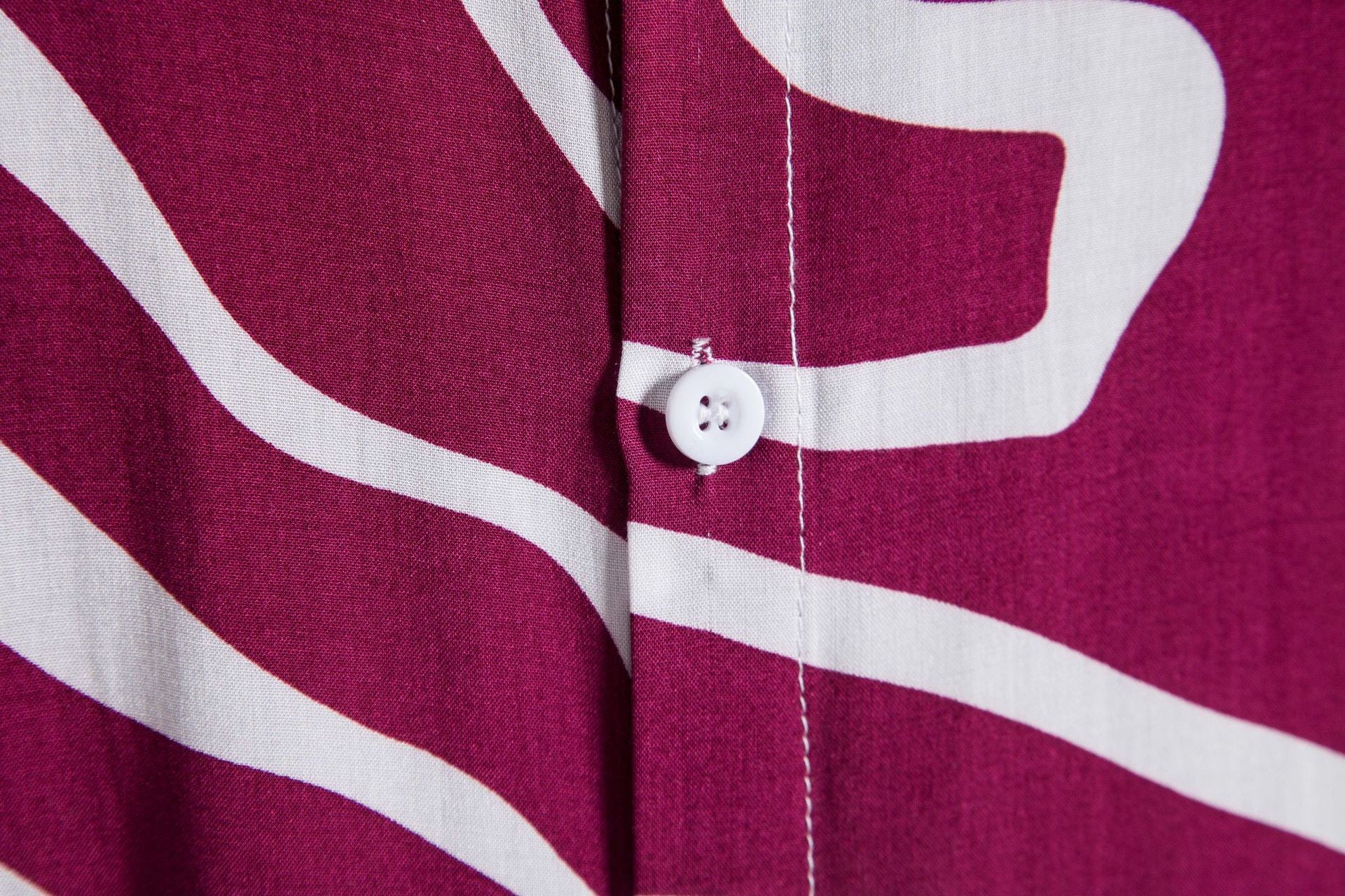 Close-up of a purple shirt with white abstract patterns and a button.