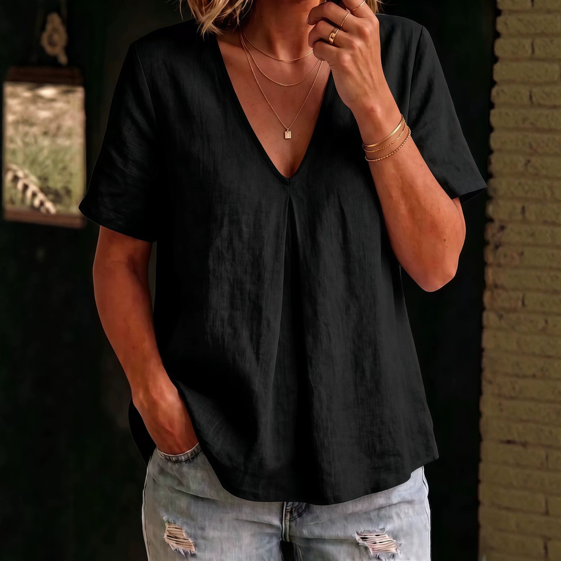 Person wearing a black top and ripped jeans with a blurred background