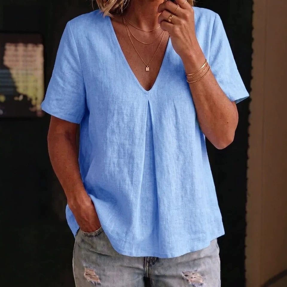 Person wearing a light blue shirt and ripped jeans indoors.