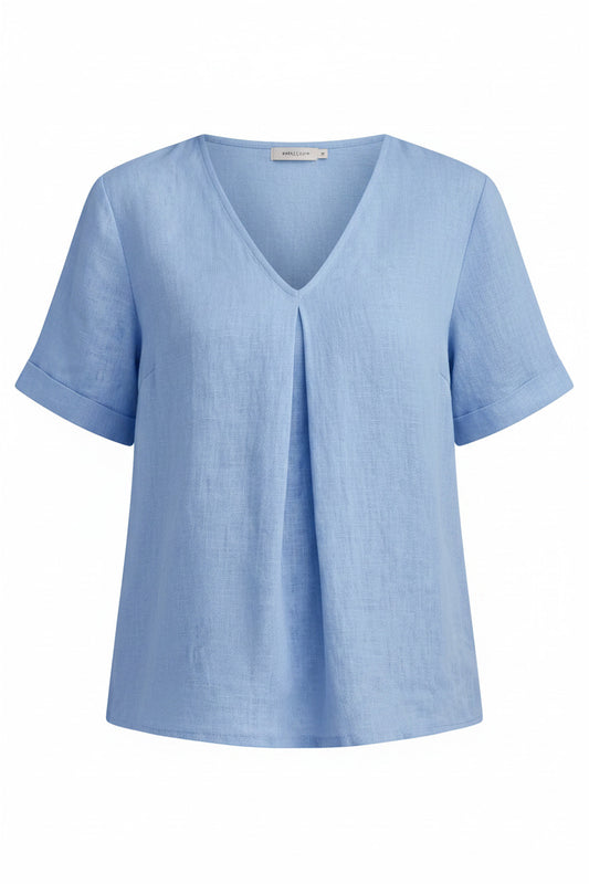 Person wearing a light blue shirt and ripped jeans indoors.