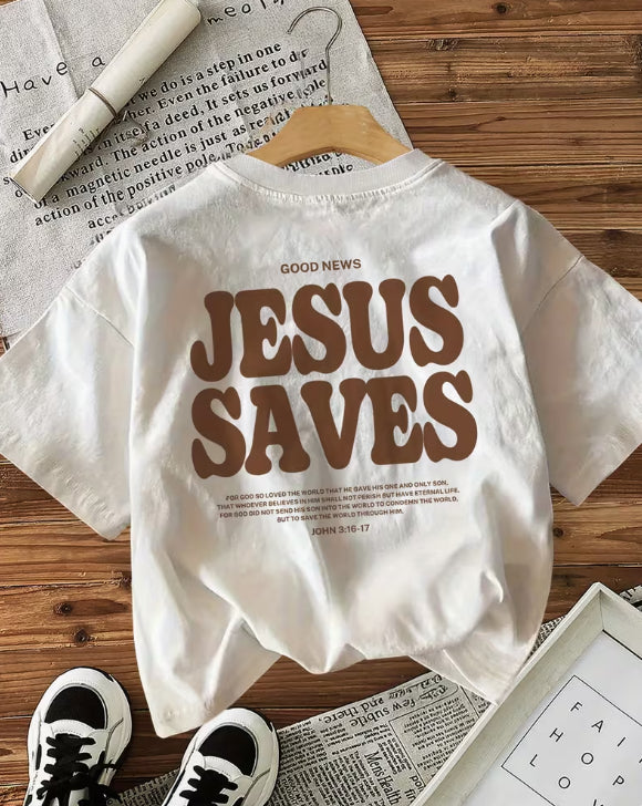 White t-shirt with 'Jesus Saves' text on a wooden surface with shoes and newspaper.