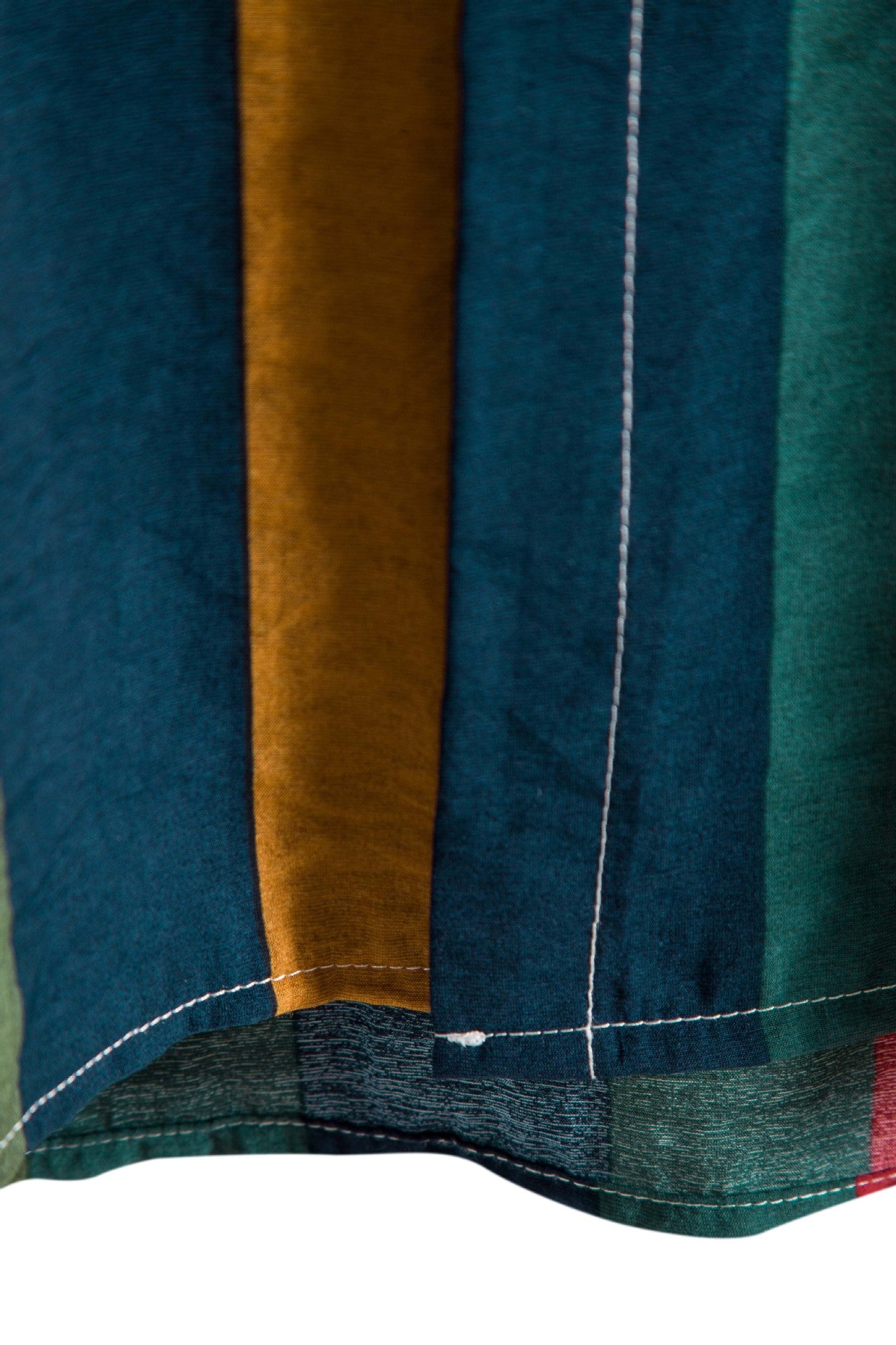 Close-up of a multicolored fabric with blue, green, and brown stripes on a white background.