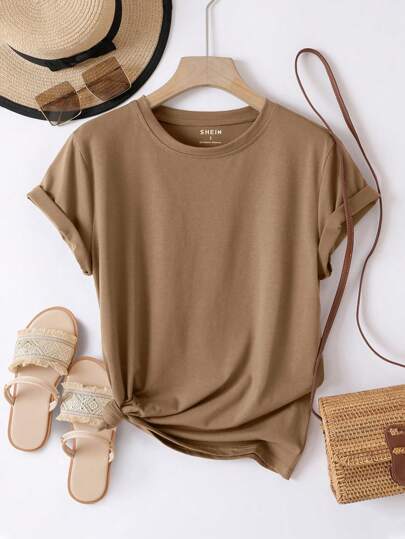 Brown t-shirt on a hanger with a straw hat, sandals, and bag on a white background