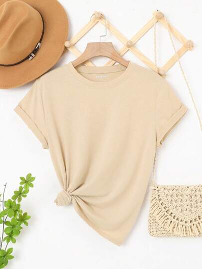 Beige t-shirt on a hanger with a hat, plant, and bag on a white background
