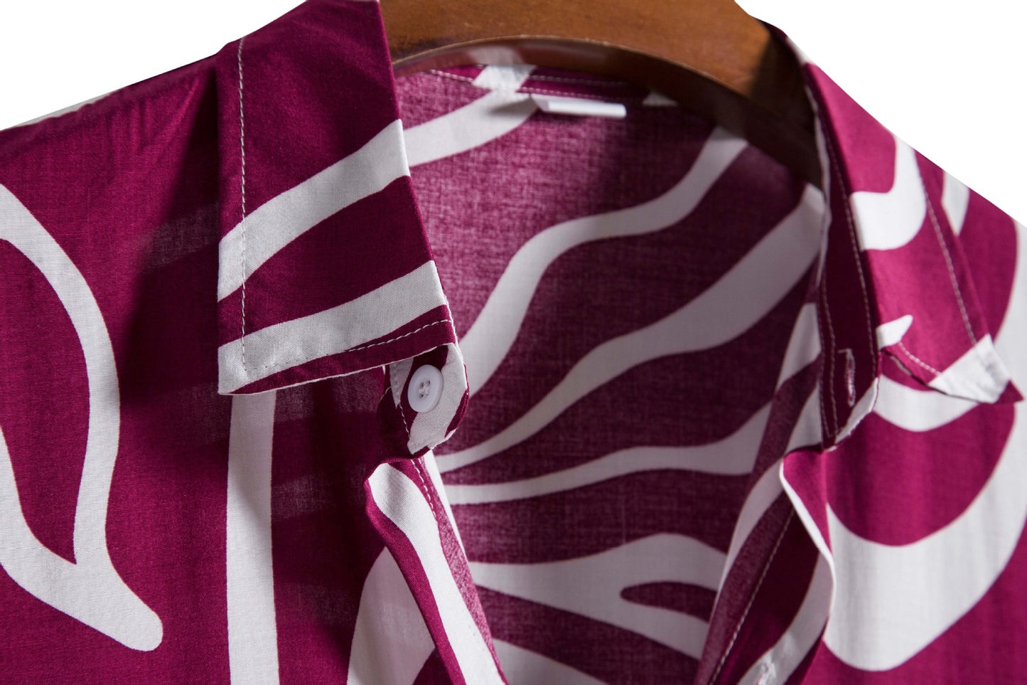 Close-up of a maroon shirt with white patterns on a wooden hanger.