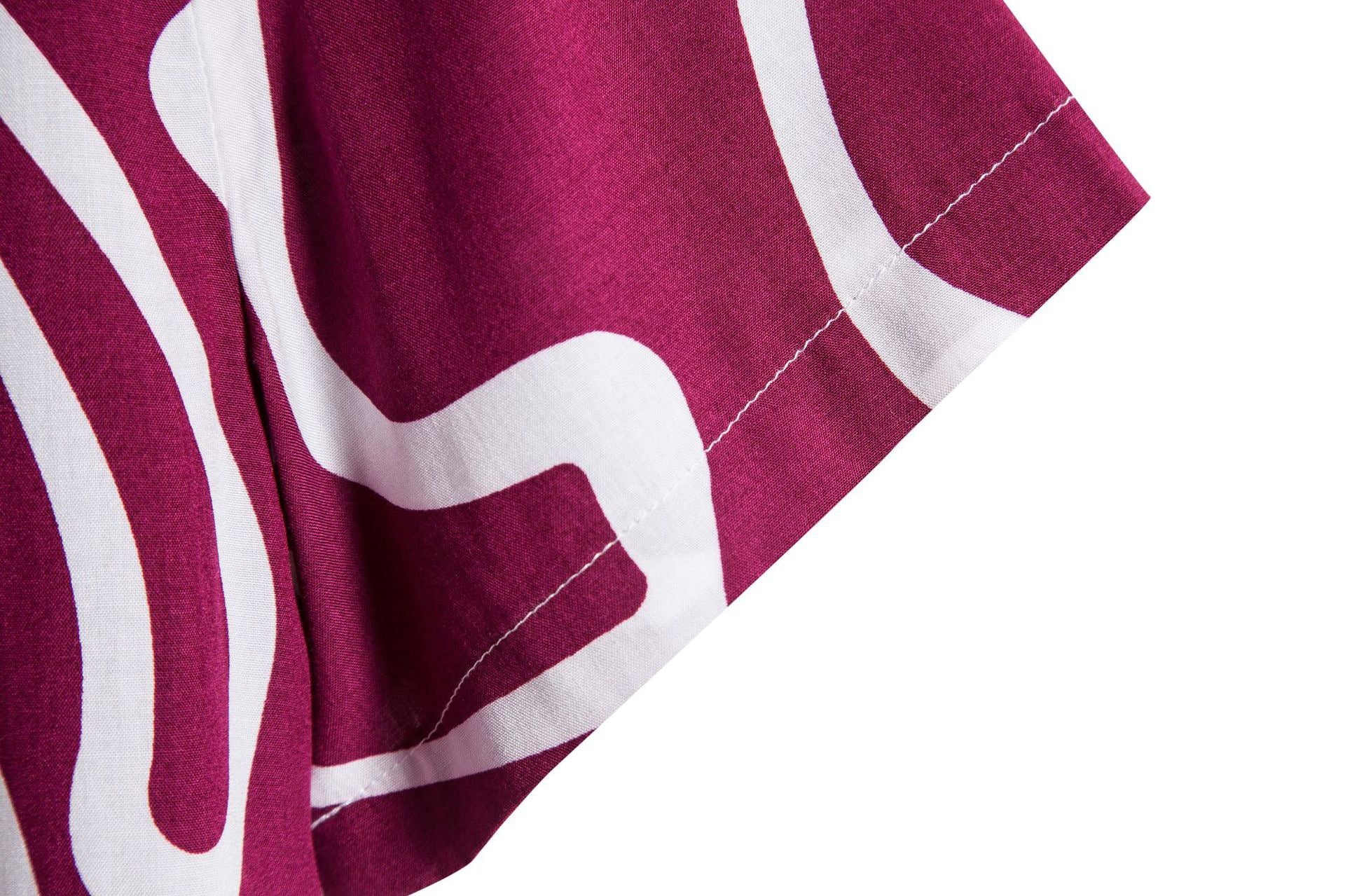 Close-up of a maroon fabric with white geometric patterns on a white background