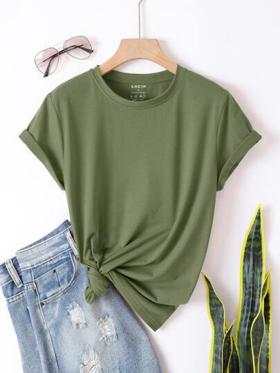 Green t-shirt with a knot detail on a hanger next to blue jeans and sunglasses.