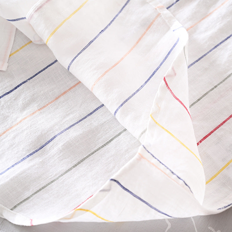 Close-up of a white fabric with colorful stripes on a tiled floor.