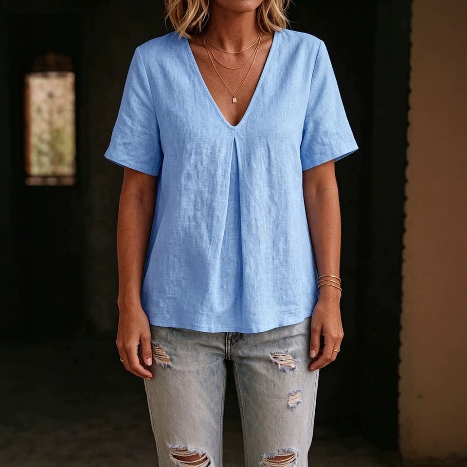 Person wearing a light blue shirt and ripped jeans against a dark background